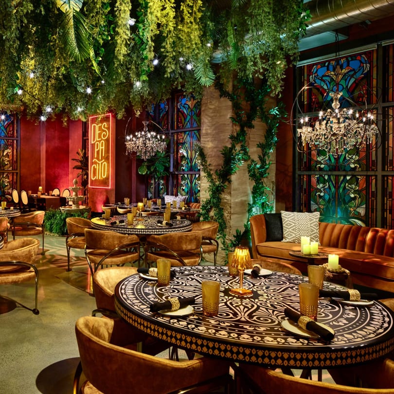 Havana 151 restaurant interior with lush greenery, ornate tables, and a "DESPACITO" neon sign.