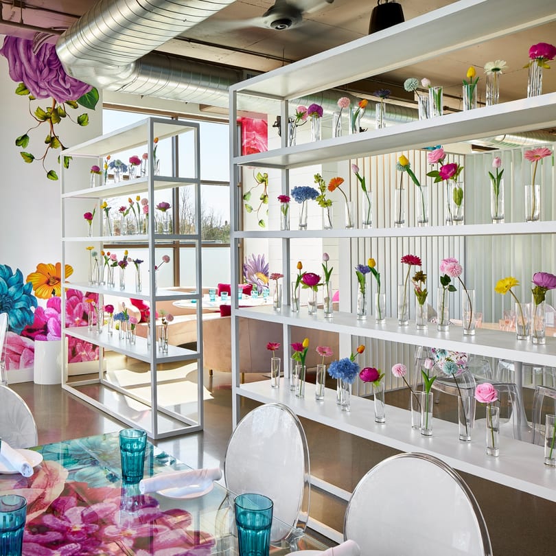 Havana 151's bright dining room with white shelves displaying colorful flowers and floral-patterned tables.
