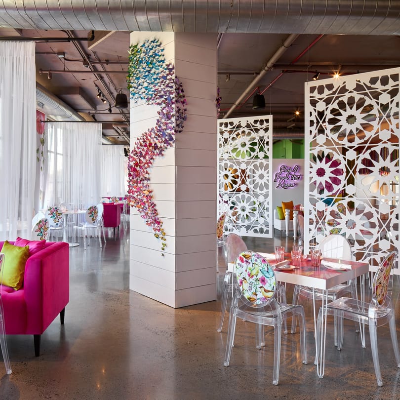 Vibrant Havana 151 dining room with butterfly art, patterned screens, and fuchsia seating.
