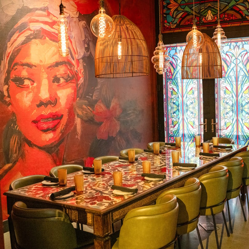 Havana 151's private dining room with a long table, green chairs, and a vibrant mural.