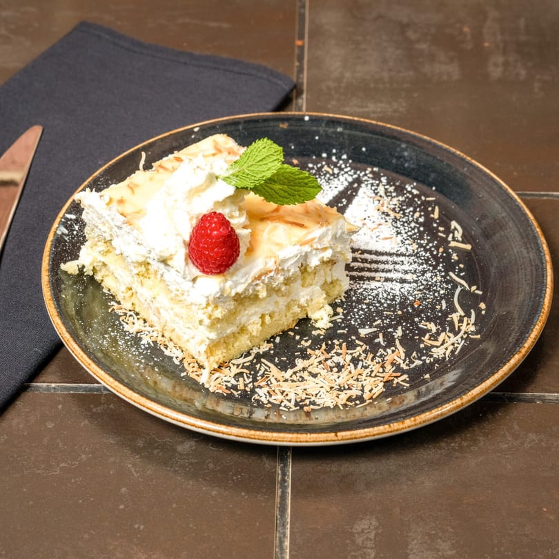 A slice of Havana 151's tres leches cake, topped with whipped cream, a raspberry, and mint.