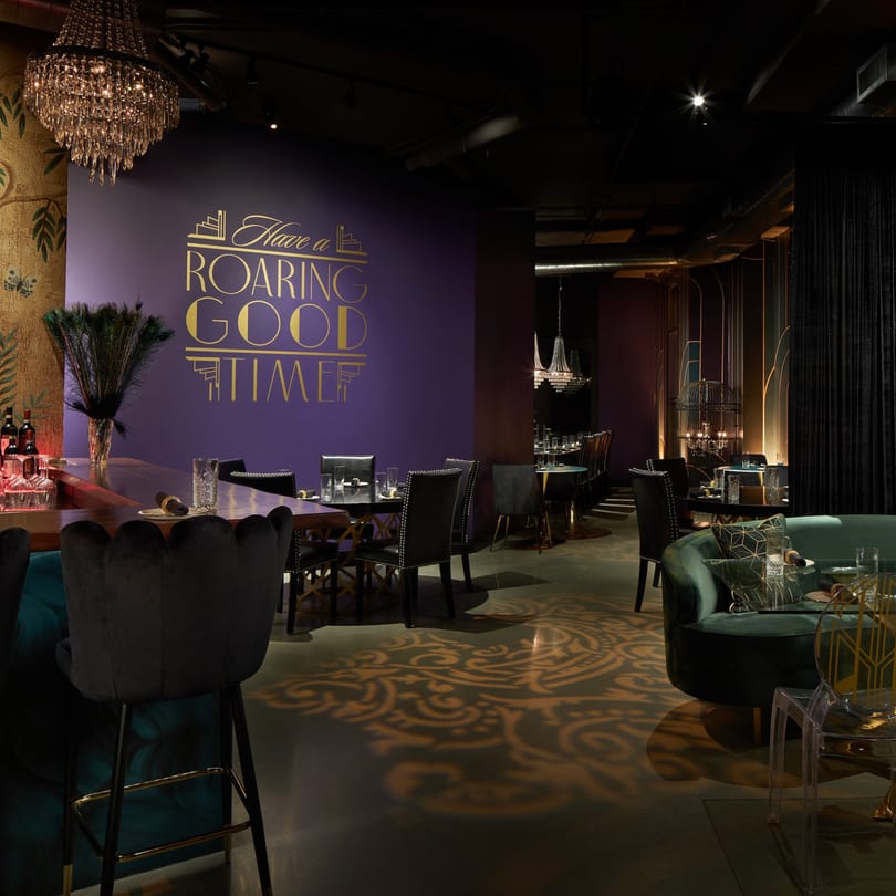 Havana 151's dimly lit dining room with purple walls, chandeliers, and elegant seating.