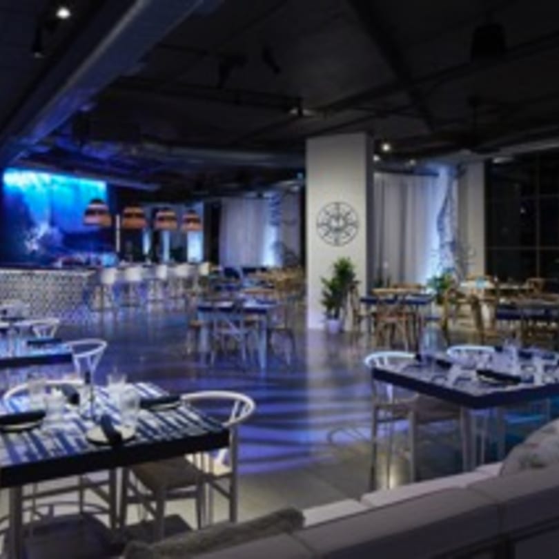 The Loft at Lena's, a dimly lit Cuban restaurant with blue lighting, tables, and a bar area.
