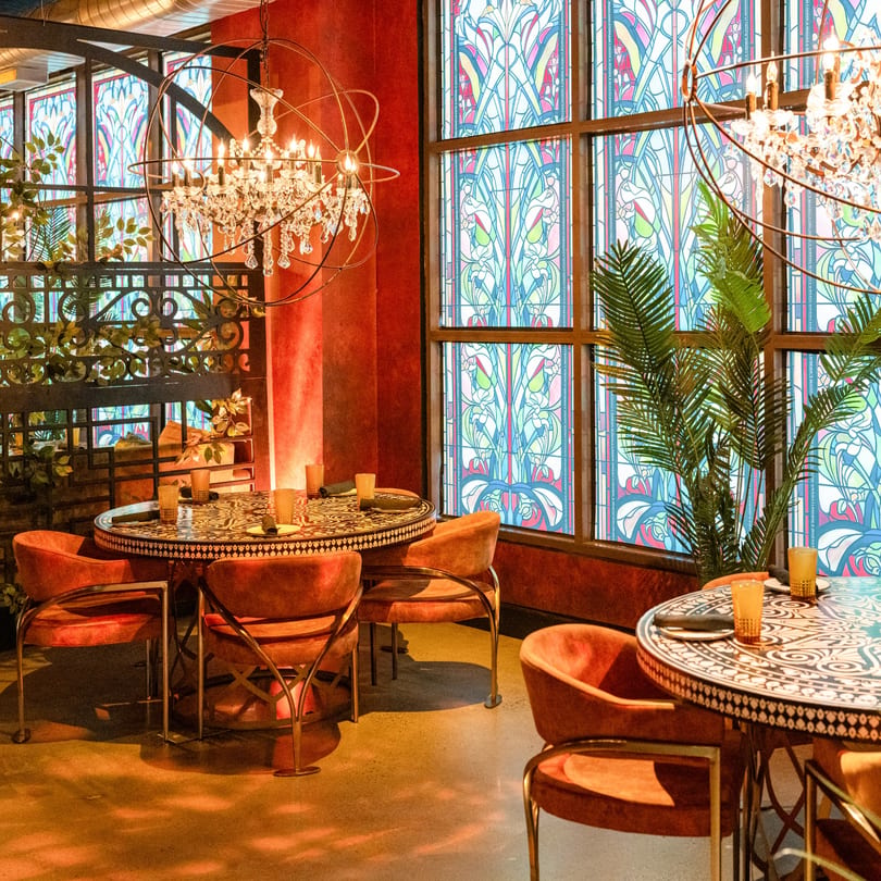 Havana 151 dining room with ornate tables, velvet chairs, chandeliers, and stained-glass windows.