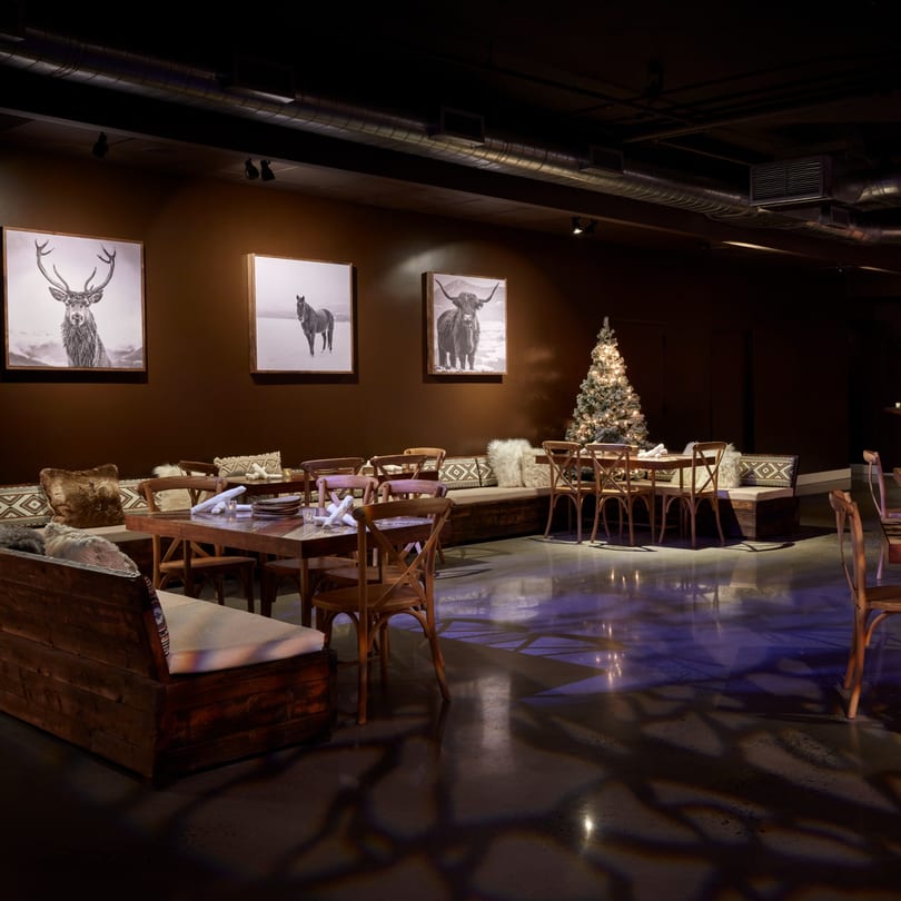 The Loft at Lena's dining area with dark walls, wooden tables, benches, and animal portraits.