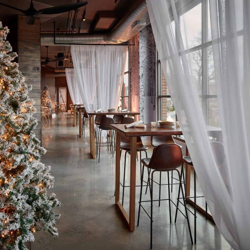 A festive Havana 151 dining room with tall tables, bar stools, and frosted Christmas trees.