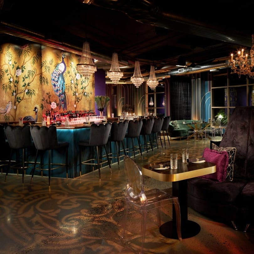 Havana 151's bar area with a peacock mural, chandeliers, and plush seating.