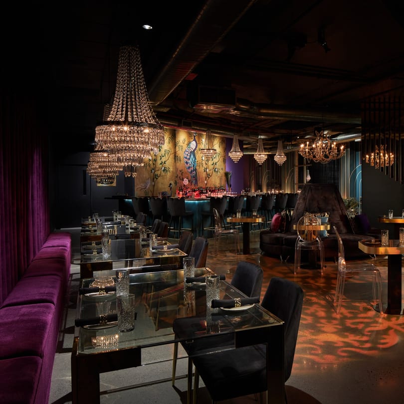 Elegant Havana 151 dining room with purple velvet seating, crystal chandeliers, and a peacock mural.