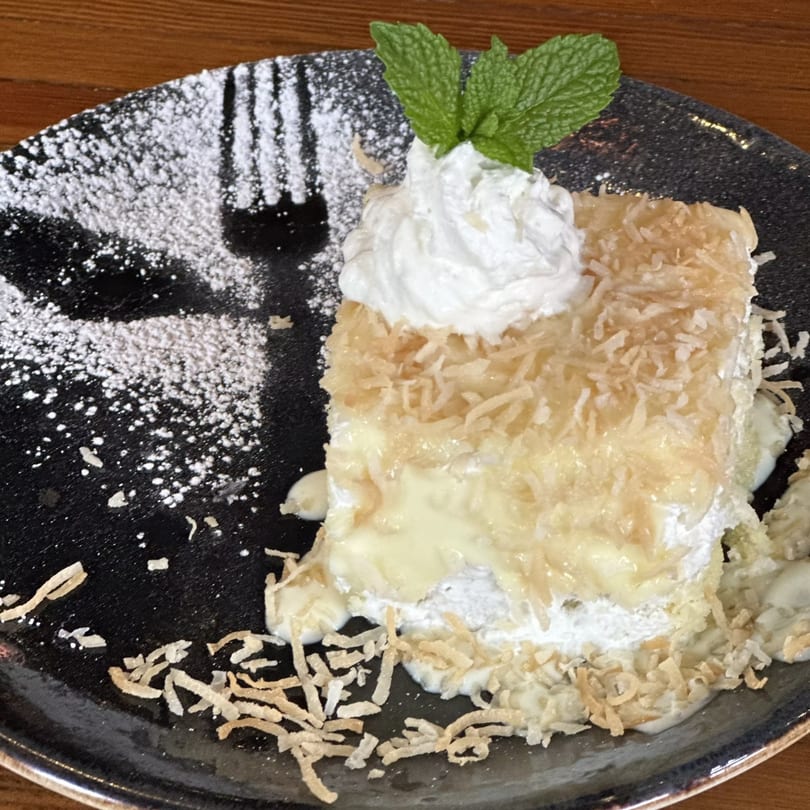 A slice of Havana 151's coconut tres leches cake, topped with whipped cream and mint.