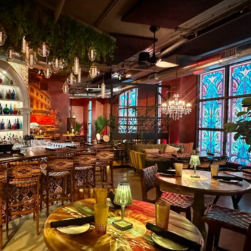 Havana 151's vibrant interior with a bar, colorful stained glass, and eclectic lighting.
