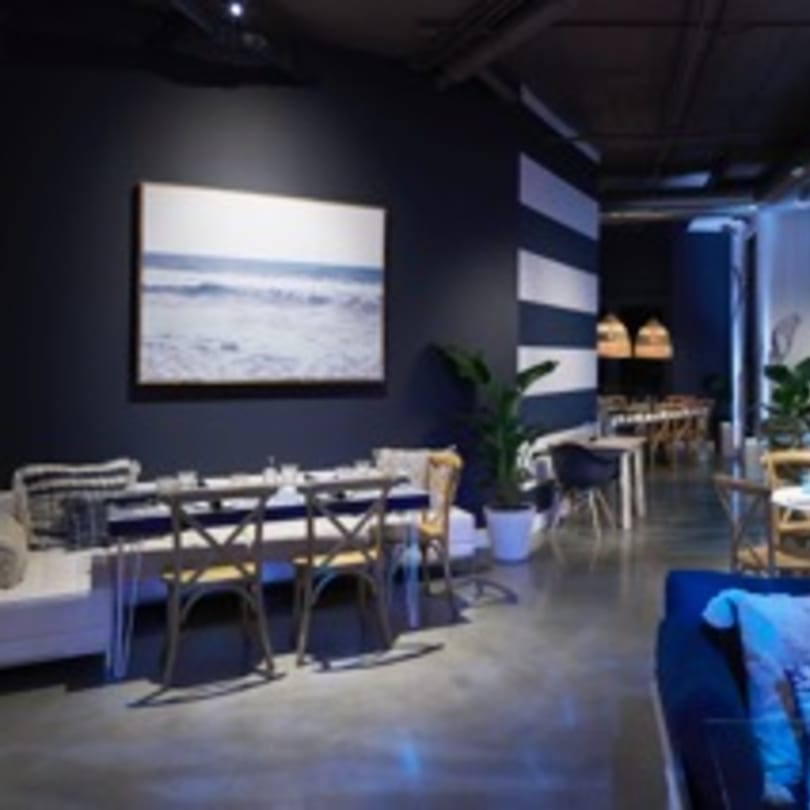 Havana 151 dining area with dark blue walls, striped accents, and ocean artwork.